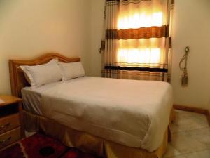 1 dormitorio con cama y ventana en Capricon Executive Hotel Kabale, en Kabale