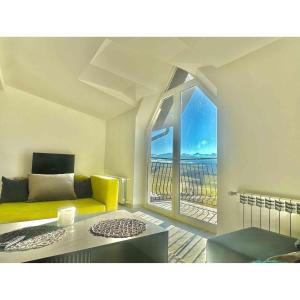 ein Wohnzimmer mit einem gelben Sofa und einem großen Fenster in der Unterkunft Mountain View Apartament Termy Chochołowskie 5 min in Suchá Hora