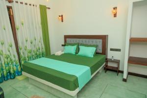 a bedroom with a bed with green sheets and blue pillows at Wind Hill Villa - Weligama in Weligama