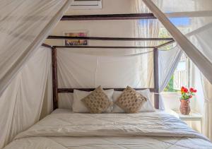 a bedroom with a canopy bed with pillows and a window at Private pool heritage villa in Cavelossim area in Velim