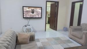 a living room with a couch and a tv on a wall at سوما للشقق المفروشه Soma apt in Al Madinah