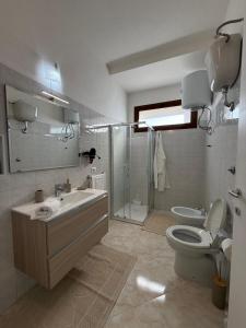 Un baño con lavabo, inodoro y ducha. en Domus Teresa, en Capoterra