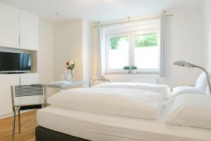 a white bedroom with two beds and a television at HOMEFY - Gasthaus Düsseldorf - Meerbusch in Meerbusch