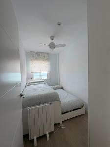 een witte slaapkamer met een bed en een raam bij Mareny de Barraquetes in Mareny Blau +25 foto's