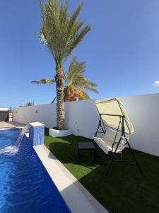 a hammock next to a swimming pool with a palm tree at Villa Douha in Midoun