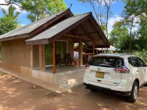 un coche aparcado frente a una casa pequeña en The Royal Lake Cabanas, en Anuradhapura