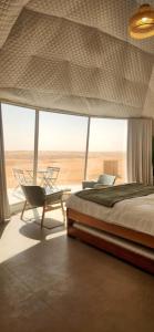 a bedroom with a bed and a chair and a window at Milky Way Domes in Bidiyah