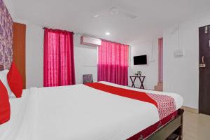 1 dormitorio con 1 cama grande y cortinas rojas en Hotel O New Lakeview Palace, en Hyderabad