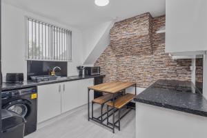 una cocina con armarios blancos y una pared de ladrillo en Luxury 2BR Retreat Sheldon, en Sheldon