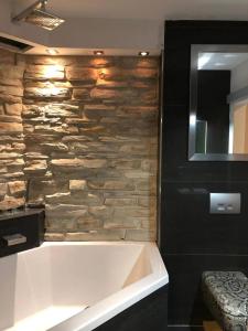 a bath tub in a bathroom with a stone wall at Cocktailpedia - Apartment mit Loggia in Wesel