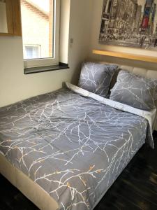 a bed with a gray comforter and a window at Cocktailpedia - Apartment mit Loggia in Wesel