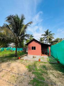 a small house with a green wall and palm trees at Siilver Sands Hutt Homestay - Malpe Beach in Malpe