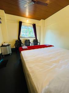 a bedroom with a large white bed and chairs at Siilver Sands Hutt Homestay - Malpe Beach in Malpe +10 photos