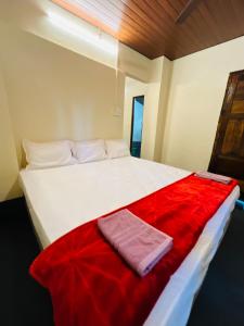 a large white bed with a red blanket on it at Siilver Sands Hutt Homestay - Malpe Beach in Malpe