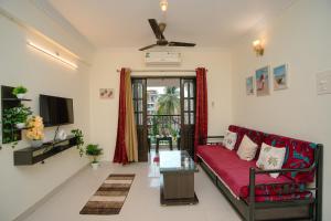 a living room with a red couch and a tv at Sukoon by Second Homes in Candolim