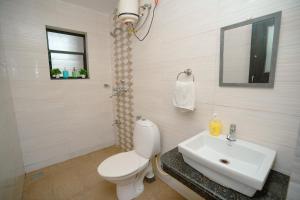 een badkamer met een toilet, een wastafel en een spiegel bij Sukoon by Second Homes in Candolim +11 foto's