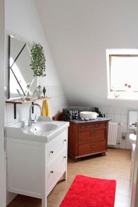 ein Badezimmer mit einem Waschbecken und einem roten Teppich in der Unterkunft SchönErleben in Schwabstedt