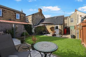 a small garden with a table and an umbrella at The Old Wash House - North East Escapes in Amble