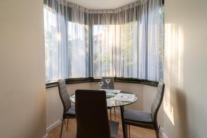 a dining room with a table and chairs and windows at Apartament Słoneczny by Grand Apartments in Sopot