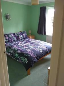 a bedroom with a bed with purple sheets and a window at Bungalow in Cambridge- 3 bedrooms in CBG