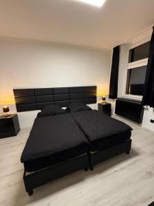 ein Schlafzimmer mit einem großen schwarzen Bett und zwei Fenstern in der Unterkunft Freshly renovated City Apartments Essen KITCHEN WIFI near Düsseldorf Airport in Essen