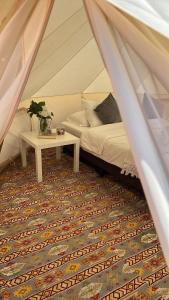 Un dormitorio con una cama y una mesa en una tienda de campaña. en Quiet Nights Camp, en Badīyah
