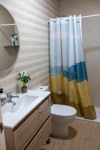 ein Badezimmer mit Waschbecken, Toilette und Duschvorhang in der Unterkunft Vivienda rural La Puentezuela in Grazalema