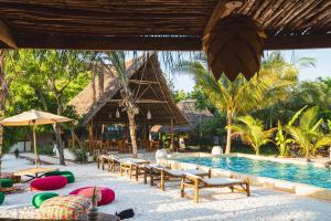a resort with a pool and lounge chairs and a resort at Hostel 197 in Nungwi
