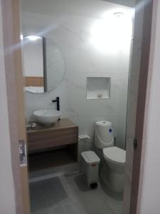 a white bathroom with a toilet and a sink at APARTAMENTO FAMIliar MELGAR v in Melgar +5 photos
