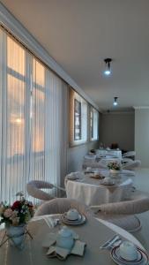 a room with white tables and chairs and windows at Hotel Santa Fé in Ponta Grossa