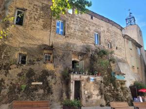 un vieux bâtiment avec deux bancs devant dans l'établissement La chouette paisible, à Villecroze
