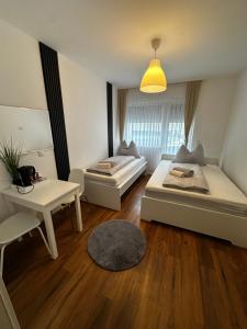 a room with two beds and a table and a desk at Zimmervermietung Wels 2 in Wels