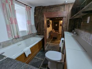 a bathroom with a tub and a toilet and a sink at Longhouse - Hen Dy in Rhayader
