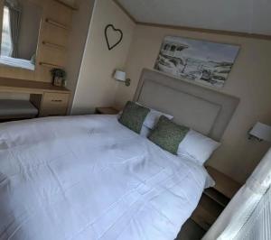 a large white bed in a small bedroom at Caravan by the Sea D09 in Kinmel Bay