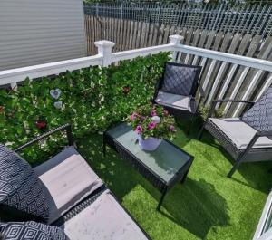 a patio with two chairs and a table with flowers at Caravan by the Sea D09 in Kinmel Bay
