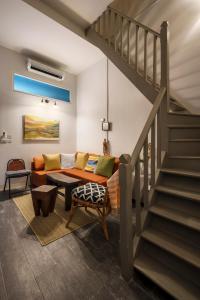 a living room with a couch and a staircase at Non Inn Entire Historic 5 Bedroom Riverside Shophouse near ICONSIAM for Families and Groups in Bang Rak