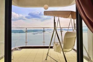 une chaise sur un balcon avec vue sur l'eau dans l'établissement Dooga Ins-Retro Dreamland Seaview Bathtub by Doogahome Homestay, à Johor Bahru