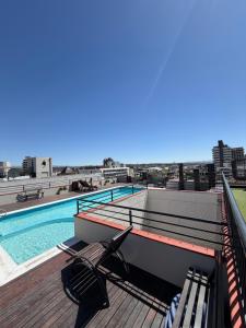 a deck with chairs and a swimming pool on a building at Depto Céntrico, Cochera, Pile, Terraza in Villa Carlos Paz +4 photos
