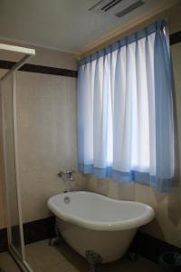 a bathroom with a bath tub and a window at Magi House in Magong