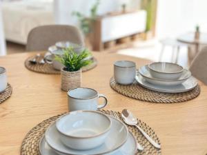 a wooden table with plates and cups and spoons at Apartament BEACH GLOW-Sand Dunes Dziwnów EPapartamenty in Dziwnów