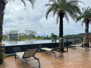 a deck with two chairs and two palm trees at Room in Kamala at Citygate Condo in Kamala Beach