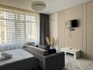 a bedroom with a bed and a couch and a tv at Astana Design Nest in Taldykolʼ