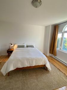 a white bedroom with a large bed and a window at Maison Acropole in Gatineau +16 photos