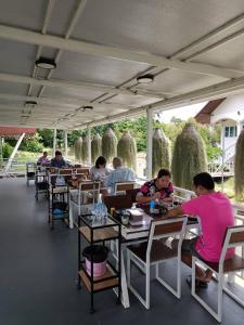 people sitting at tables in a restaurant with hay bales at Pun's Garden Home in Ban Sao Thong