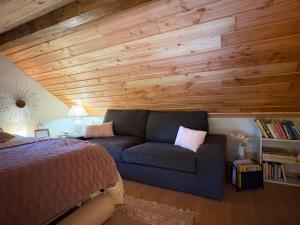 a bedroom with a blue couch and a wooden ceiling at La cabane sur l'étang in Étival-Clairefontaine