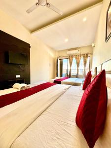 a large bedroom with two beds with red pillows at Hotel JB Grand Residency Zirakpur Chandigarh # lift #Balcony Rooms # Banquet Hall # Family Rooms in Chandīgarh +34 photos