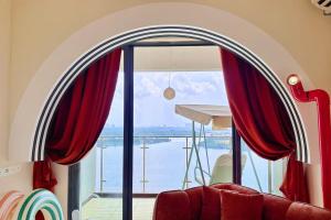 a room with a large window with red curtains at Dooga Ins-Retro Wonderland Seaview Bathtub by Doogahome Homestay in Johor Bahru