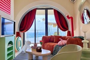 a living room with a red couch and a large window at Dooga Ins-Retro Wonderland Seaview Bathtub by Doogahome Homestay in Johor Bahru