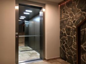 a walk in shower in a bathroom with a stone wall at Ahorn Chalet Mittelberg in Mittelberg