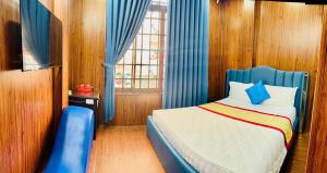 a bedroom with a bed with blue curtains and a window at royal hotel bà điểm hồ chi minh in Ho Chi Minh City +11 photos